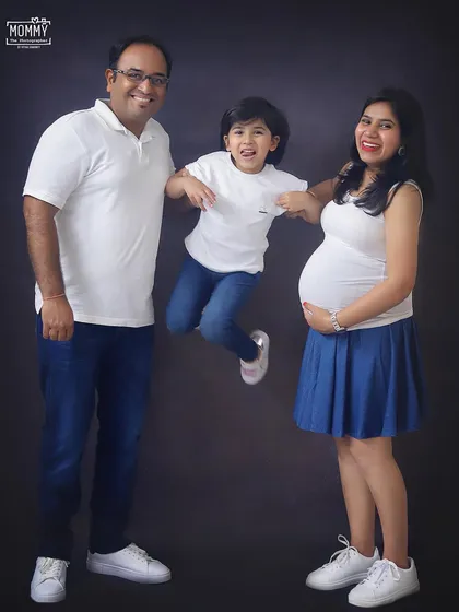 Pure family fun in the studio. Capturing the older sister's joyful jump is what makes this casual family maternity photo so full of life and personality.