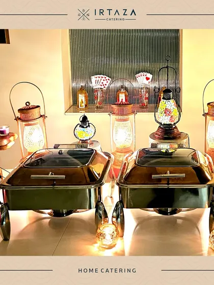 A cozy home catering display with decorative lanterns and silver chafing dishes. This setup is perfect for creating a warm and inviting atmosphere for a small dinner party.