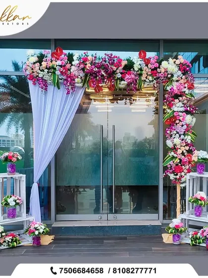 A floral entrance arch for an indoor event, using a mix of colorful flowers and white drapes to create a fresh and welcoming feel.