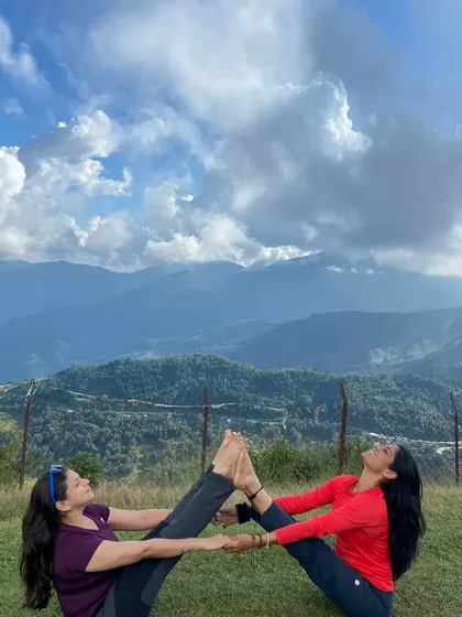 A beautiful partner boat pose, Navasana, with the clouds and mountains as our audience. This pose builds core strength and a deep sense of partnership.