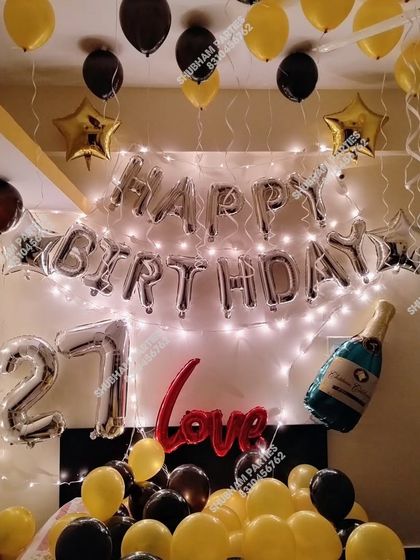 A 27th birthday home decoration with black, yellow, and silver balloons.