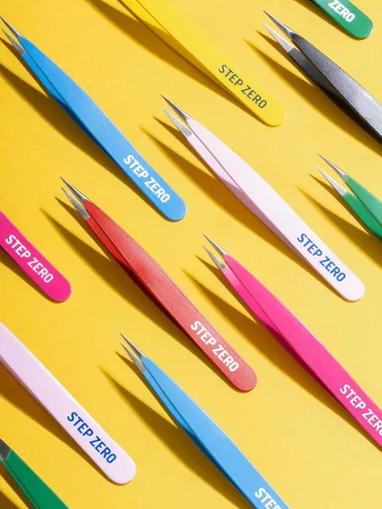 A dynamic, colorful flat lay of Step Zero tweezers. The repetitive pattern and bright yellow background create a visually arresting image for social media and e-commerce banners.