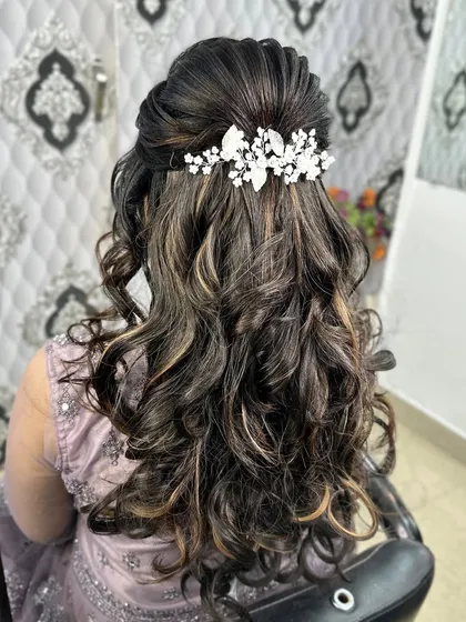 A half-up, half-down hairstyle with voluminous curls. This look is perfect for a reception or engagement and is finished with a beautiful crystal hair accessory.