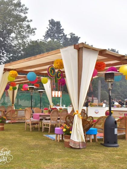 A wide view of the fiesta setup, showing the use of pergolas to create defined seating areas within the large lawn.