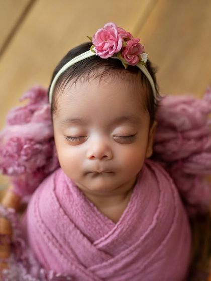 A close-up on her sweet face. The pink floral headband perfectly matches the roses, tying the whole theme together.