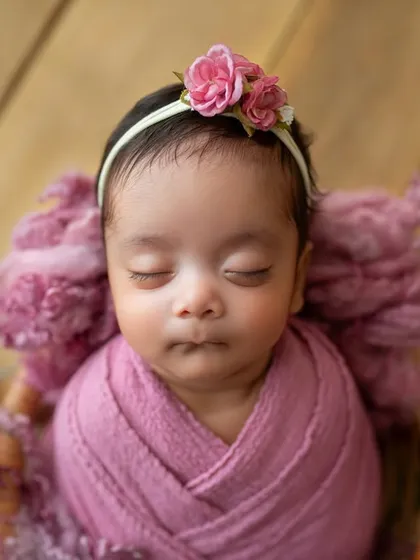 A close-up on her sweet face. The pink floral headband perfectly matches the roses, tying the whole theme together.