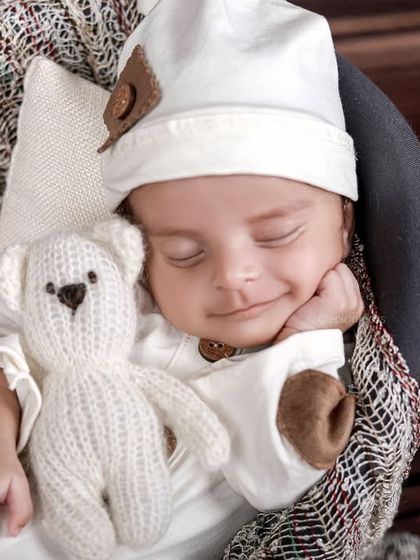 A delightful smiling portrait of a baby cuddling a teddy bear. These happy accidents are the most precious moments to capture.
