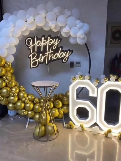 Celebrating a 60th birthday with a classic gold and white theme. The circular balloon arch and large light-up '60' create an elegant and memorable photo spot.