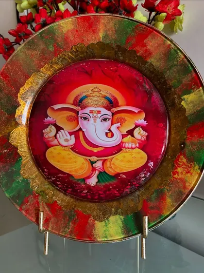 A vibrant decoupage plate featuring Lord Ganesha, perfect for celebrating Ganesh Chaturthi. The rich colors and gold border make it a beautiful decorative piece.