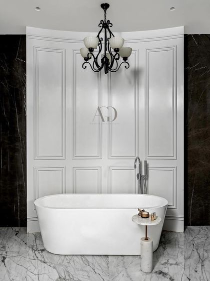 The same bathroom seen from the front, showcasing the beautiful contrast between the white tub and paneling and the dark, dramatic marble walls. The curved back wall adds a soft, sculptural element to the room.