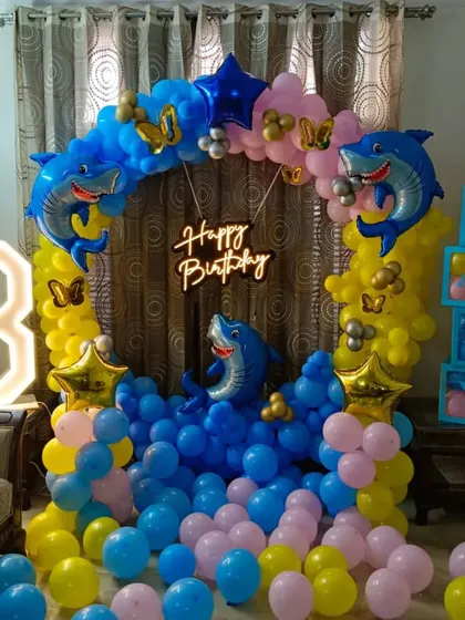 A fun Baby Shark theme for an 8th birthday party at home. This setup features a circular balloon arch with shark foils and a large marquee number '8'.