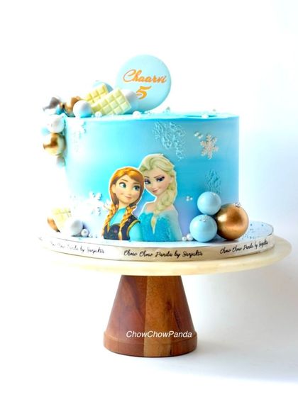 Here is another take on a Frozen theme cake, this time featuring both Anna and Elsa. This Chocolate Truffle cake has a blue buttercream finish with snowflake details and decorative spheres.