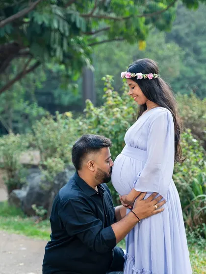 A classic and tender maternity pose. The dad-to-be kisses the baby bump, showing his love and excitement for the little one on the way.