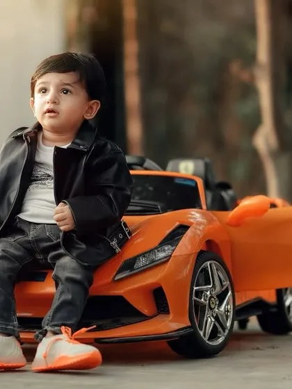 This little guy looks like a future movie star, posing coolly on his orange sports car. The leather jacket completes the look for this fun and stylish outdoor shoot.