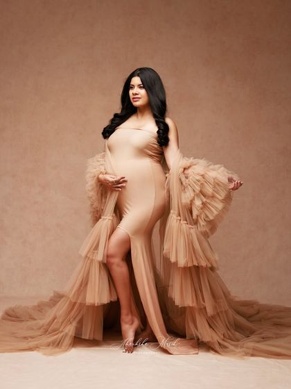 A standing portrait in a flowing nude gown, showcasing its beautiful texture and the elegant silhouette it creates.