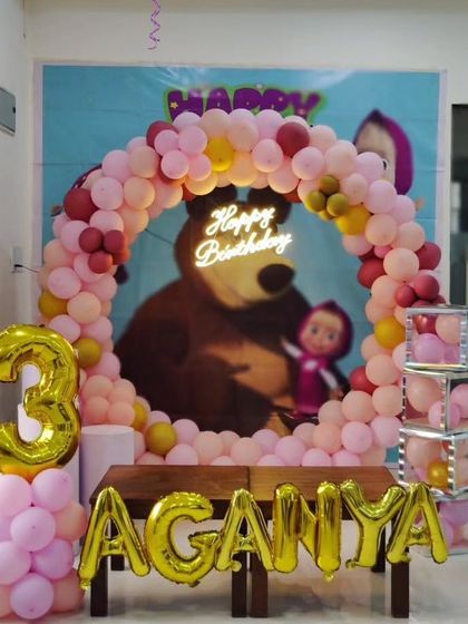 A "Masha and the Bear" themed 3rd birthday party, featuring a circular balloon arch, neon sign, and foil name and number balloons.