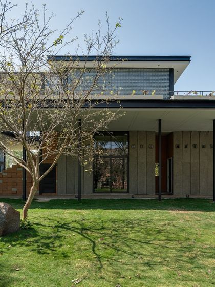 The clean lines of the architecture are softened by the presence of a young tree in the foreground. We believe in designing spaces that allow nature to grow and intertwine with the built form over time.