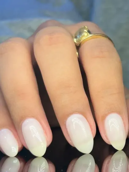 A clean and simple manicure with a milky white polish on almond-shaped nails.