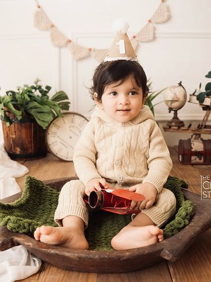A full view of the rustic, travel-themed first birthday setup, with the birthday boy sitting in a wooden bowl, ready for his next adventure.