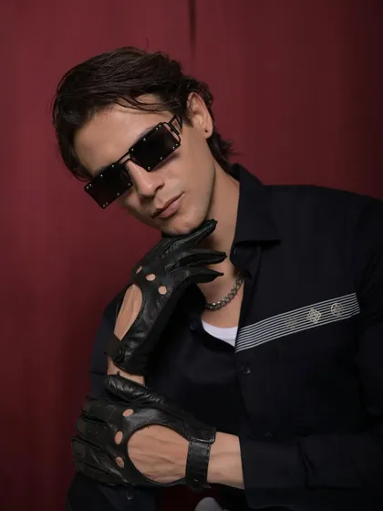 Another look from the Cairon campaign, combining a modern striped shirt with edgy accessories like sunglasses and driving gloves to embody the "young money" aesthetic.