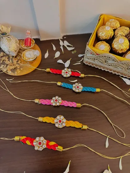 These vibrant, colorful rakhis feature a braided thread and a stone-studded floral centerpiece. They are perfect for adding a pop of color and sparkle to your Raksha Bandhan celebrations.