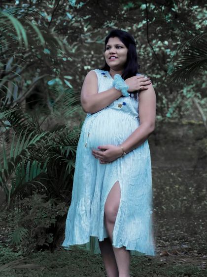 A serene solo portrait in a beautiful, simple white dress amidst lush greenery. This photo captures a quiet moment of reflection and connection with nature and the baby.