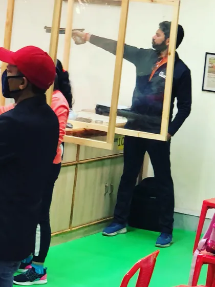 We adapted our training during the pandemic to ensure safety without compromising on quality. Here, a shooter practices his aim with a protective screen in place, a testament to our commitment to our students' well-being.