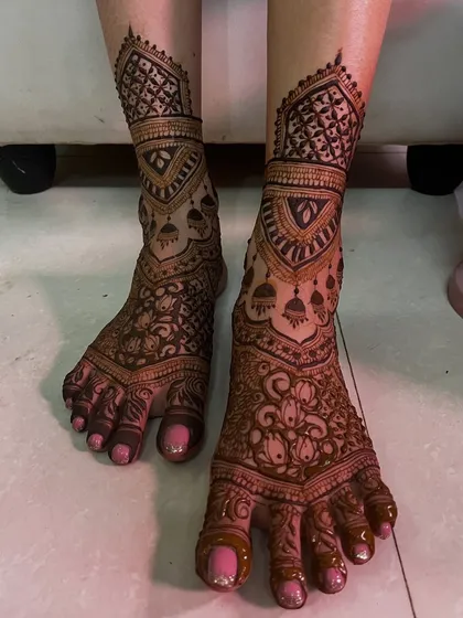 A beautiful and intricate design for a bride's feet, with jhumka and lotus motifs. The pattern is dense and detailed, perfect for a grand celebration.