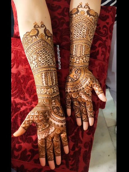 A gorgeous Karwa Chauth design with traditional peacock motifs at the top of the arm, flowing into detailed patterns down to the fingertips.