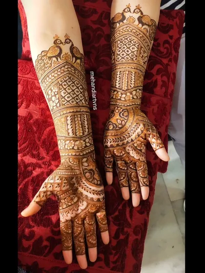 A gorgeous Karwa Chauth design with traditional peacock motifs at the top of the arm, flowing into detailed patterns down to the fingertips.