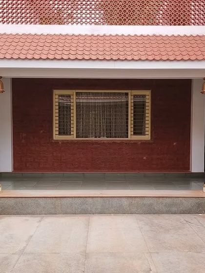 The central courtyard of the "Grid in the Grove" farmhouse, featuring traditional wooden pillars and a terracotta tile roof. This space is designed to be the heart of the home, open to the sky and connected to nature.