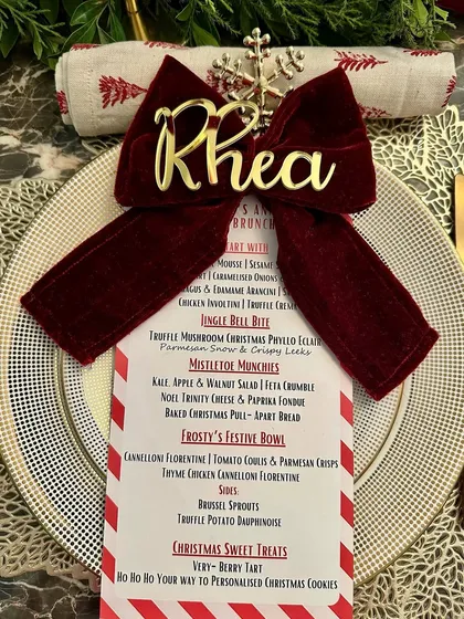A festive place setting from a Christmas sit-down brunch, complete with a personalized name card, a themed menu, and a touch of holiday sparkle.