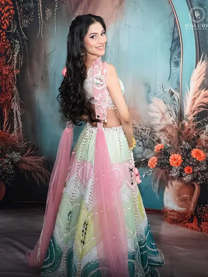 A full-length shot from the side, showing how the pastel lehenga flows. The hairstyle and makeup are designed to look beautiful from every angle.