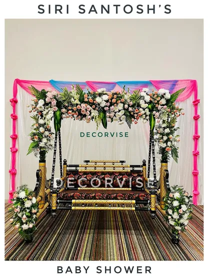 The traditional swing, or jhoola, is the heart of many baby showers. Here, we've decorated it with beautiful arrangements of fresh roses and lilies, set against a simple draped backdrop to make the floral work stand out.
