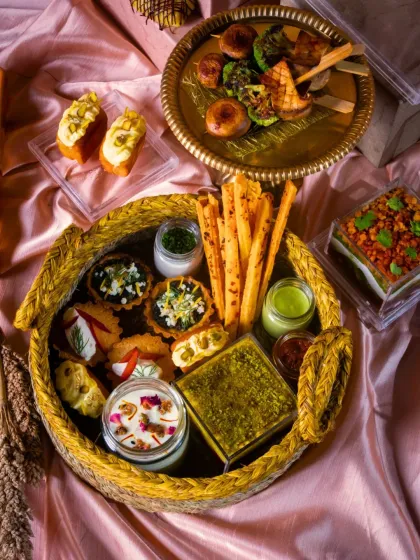 A beautiful festive platter showcasing a variety of savory bites. It includes mini quiches, cheese straws, dips, and skewers, all artfully arranged in a rustic woven basket.