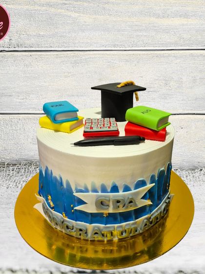 A perfect cake to celebrate a major career achievement. This CPA graduation cake is topped with edible books, a calculator, and a graduation cap.