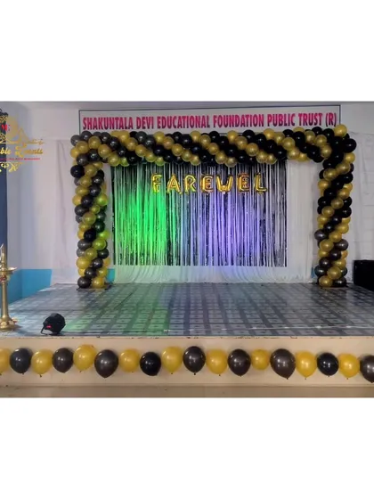 I designed this stage for a farewell party at the Shakuntala Devi Educational Foundation. The setup features a black and gold spiral balloon arch over a shimmer curtain backdrop, creating a formal and celebratory space for the event.