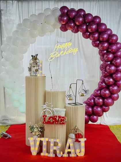A simple and sweet birthday decoration with a half-arch of white and magenta balloons. This setup is perfect for outdoor or daytime events.