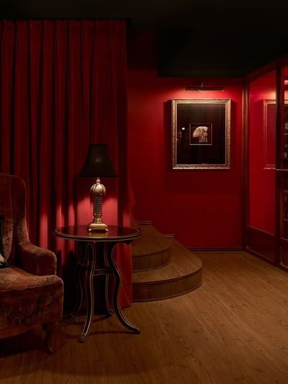 The foyer of the ZLB23 speakeasy, where deep red walls and a plush velvet armchair create an atmosphere of vintage luxury. The design guides guests through a series of unfolding spaces, building anticipation.