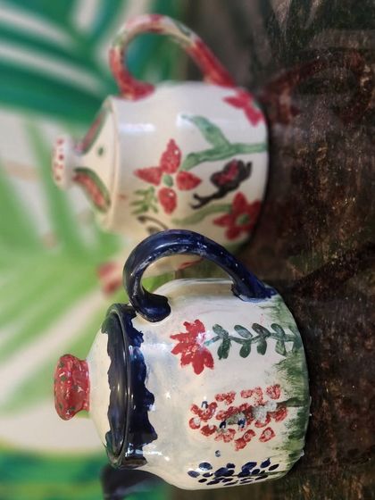 Two beautifully painted miniature watering cans, each with a unique floral design, created by our talented guests.