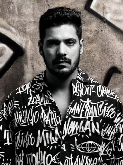 A powerful black and white portrait. The graffiti background and intense expression complement the urban style of the shirt, creating a raw and impactful fashion image.