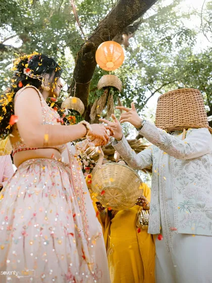 A hilarious moment where the groom has a wicker basket over his head while dancing with the bride during their Haldi.
