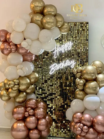A close-up of a glamorous birthday backdrop, combining a shimmering gold sequin panel with an organic arrangement of rose gold, white, and gold chrome balloons for a luxurious and high-impact look.