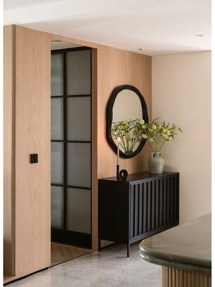 This detail shot from the Noir Blanc House shows a black fluted console and an abstract mirror against an oak-paneled wall, a perfect example of mixing textures and materials for a sophisticated look.