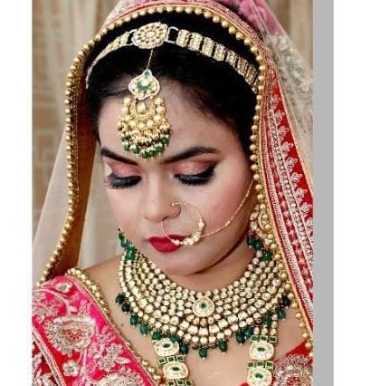 A close-up of a bride with beautiful makeup and jewellery. The green beaded Kundan set with a matching nath and matha patti is a classic choice.