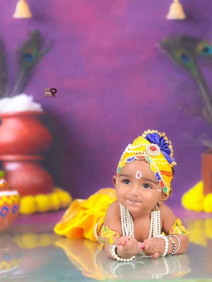 A different pose from the Little Krishna session, with the baby lying down and looking curious. The reflection on the floor adds a professional and artistic touch to the photo.