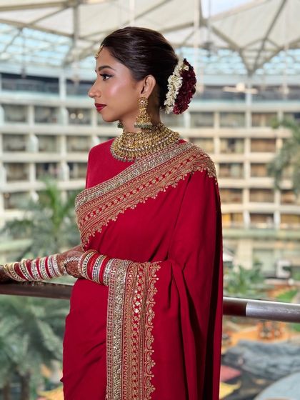 A profile view that beautifully displays the elegant hair bun with flowers and the sharp, clean lines of her makeup.