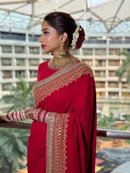 A side view of a sleek bridal bun with red and white flowers. This angle shows the clean lines and precision of the hairstyle, which provides a great foundation for setting the bridal veil.
