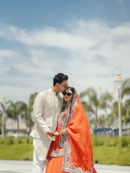 A tender moment with the groom kissing his bride's forehead against a bright blue sky. This simple, heartfelt gesture makes for a beautiful and intimate portrait.
