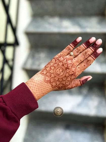 A beautiful mandala design for Diwali. The central flower has the initial 'S' inside, and the wrist is decorated with a simple net pattern.